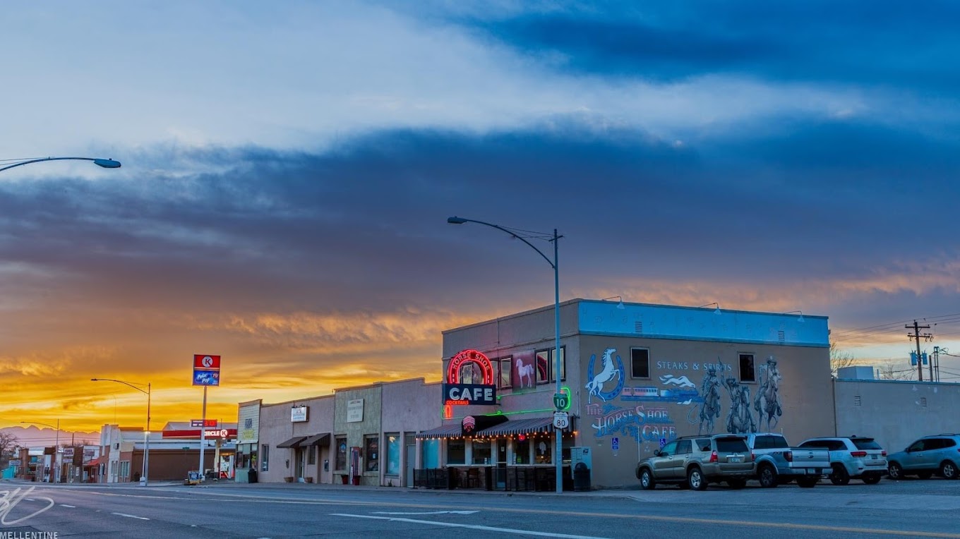 The Horseshoe Cafe at sunset — its neon sign, cowboy mural, and the Highway 80 shield in downtown Benson